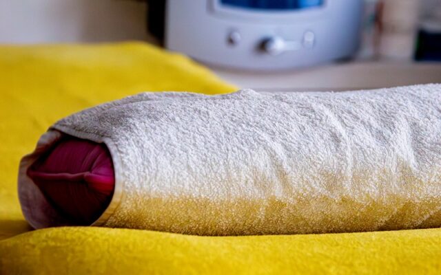 Behandlungsliege für Darmspülung mit Handtüchern und im Hintergrund das hermetisch abgeriegelte Darmspülgerät.