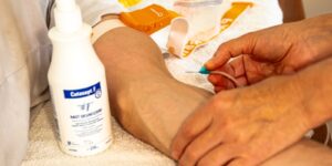 Infusionsnadel Eine Infusionsnadel die an einen Patientenarm geführt wird.