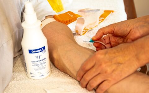 Eine Infusionsnadel die an einen Patientenarm geführt wird.